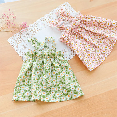 Two KittyNook Summer Cotton Cat Dresses, one green daisy, one pink floral, displayed on a wooden table.
